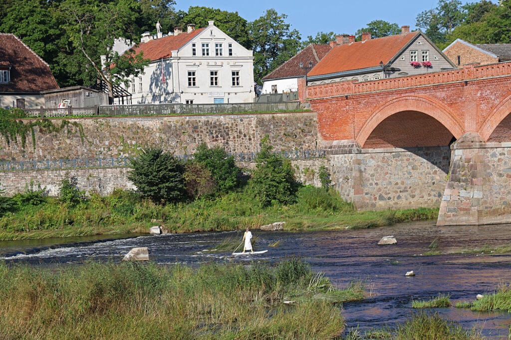 Bron med en surfare nedanför vattenfallet i Kuldiga, Lettland.