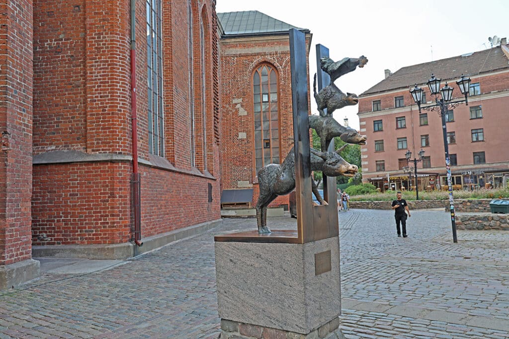 ’Musicians of Bremen' sculpture in Rīga
I bröderna Grimms saga: Bremens stadsmusikanter”, står de fyra djuren (åsna, hund, katt och tupp) på varandras rygg och kikar in i ett rövarhus och festar. Statyn skänkt till Riga av deras systerstad Bremen, har en politisk satirisk klang. De fyra djuren står på varandras rygg men tittar genom,”järnridån”