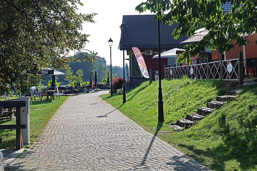 Strandpromenaden som är kantad av serveringar leder fram till en träbro över till Slottet. 