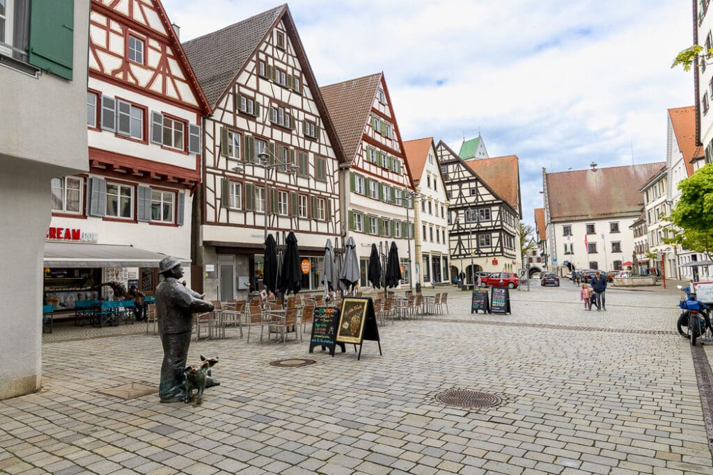 Statyn: En man med tre grisar, står fint placerade på Marktplatz.